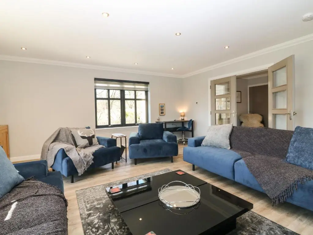 a living room with blue couches and a table at Woodend Croft in Ellon