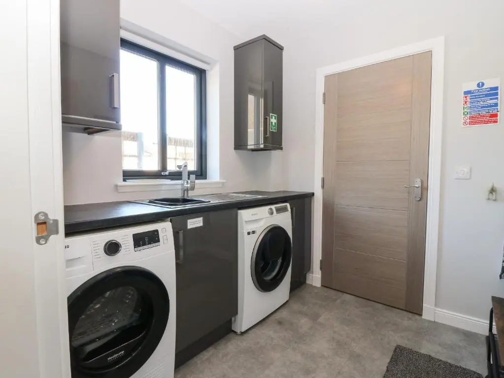 a kitchen with a washing machine and a sink at Woodend Croft in Ellon