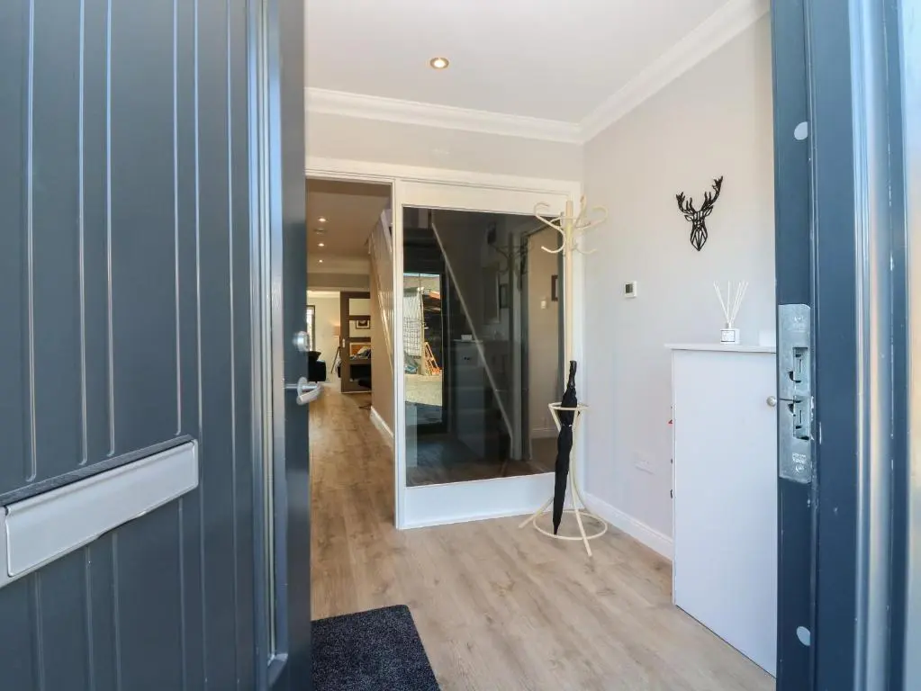a hallway with a blue door and a mirror at Woodend Croft in Ellon