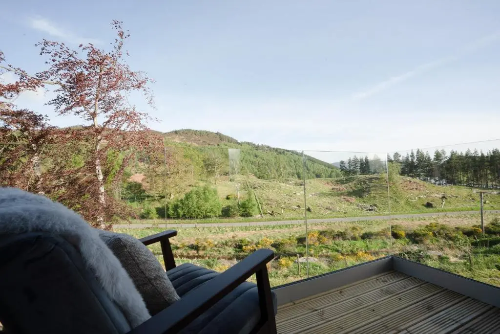 a chair on a balcony with a view of a mountain at Pityoulish Steading - Seasgair Lodges in Aviemore