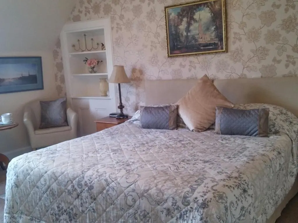 a bedroom with a large bed and a chair at Heathcote B&B in Inverness
