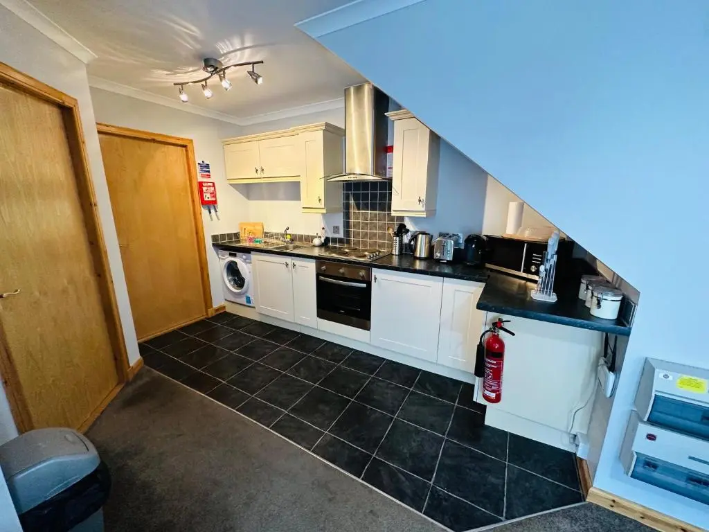 a kitchen with white cabinets and black tile floors at The Old Salt House, Flat1 in Wick
