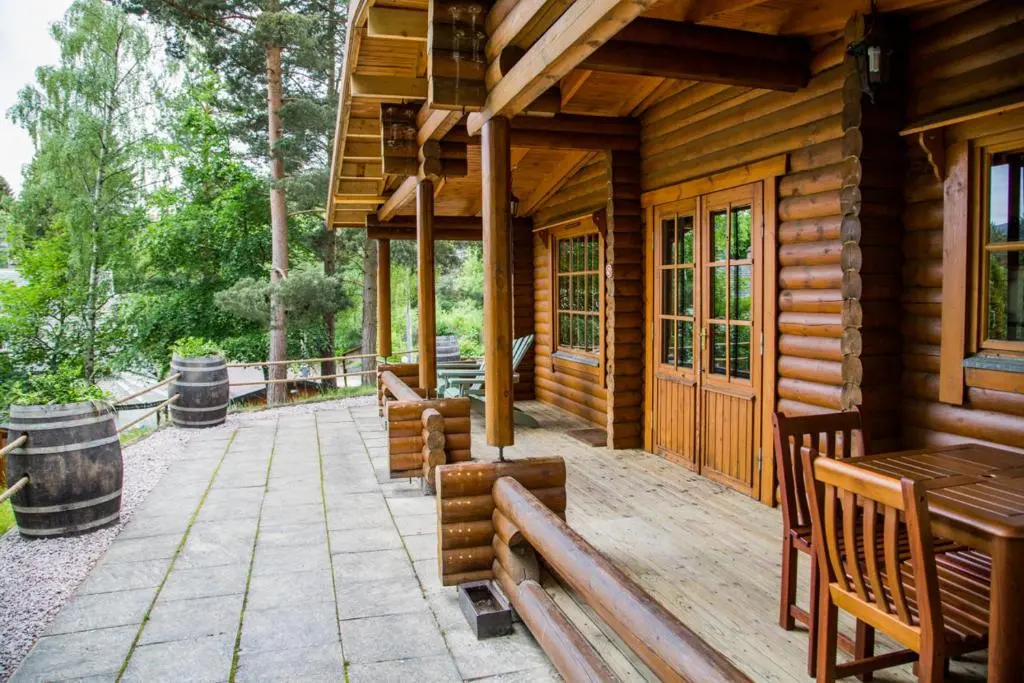 a porch of a wooden cabin with benches and tables at Bynack in Aviemore