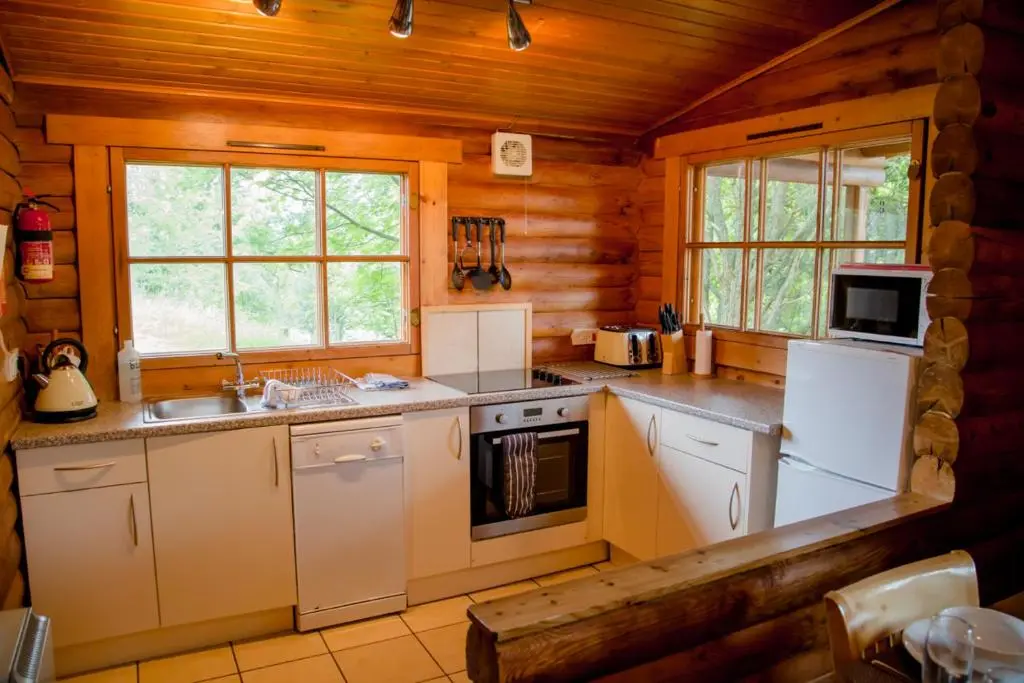 a kitchen with white appliances in a log cabin at Bynack in Aviemore