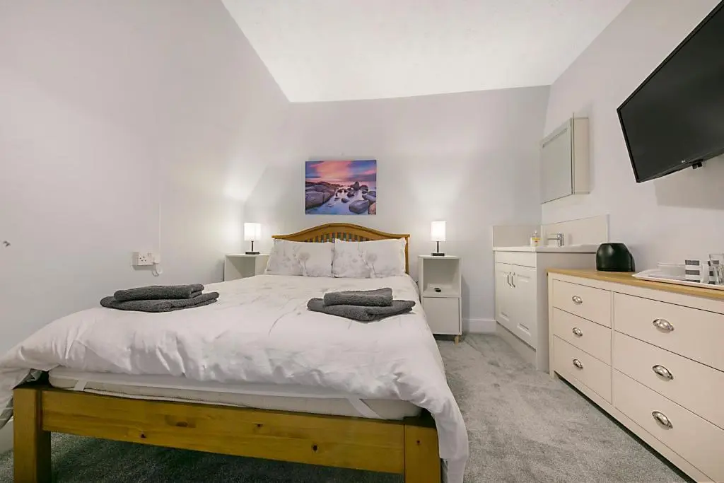 a white bedroom with a large bed and a flat screen tv at Constancevilla B8 - Grampian Lettings Ltd in Aberdeen