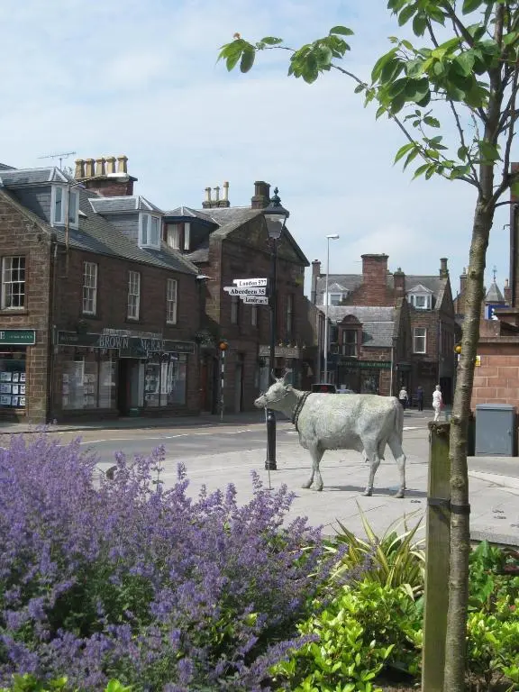 a statue of a cow walking down a street at Ardmuir in Turriff