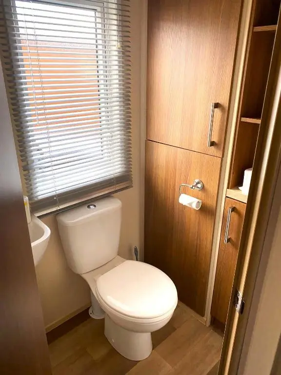 a bathroom with a white toilet and a window at Cabin 38 in Aviemore