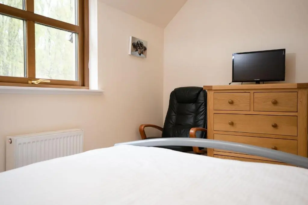 a bedroom with a bed and a tv and a chair at Bracken House in Aviemore