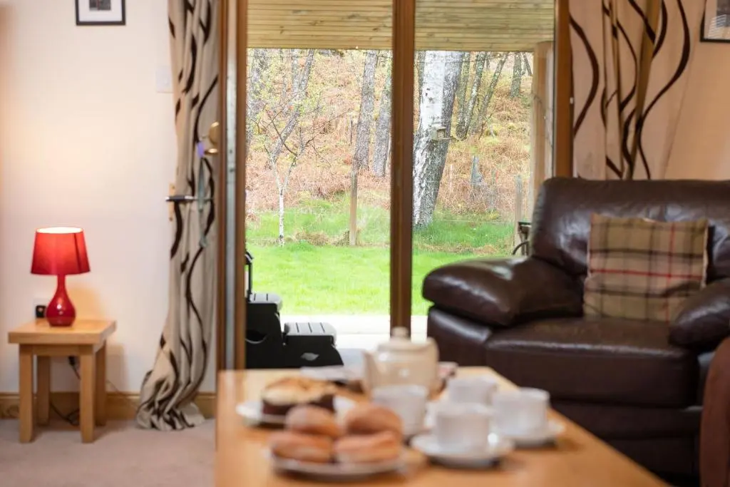 a living room with a leather couch and a table at Bracken House in Aviemore
