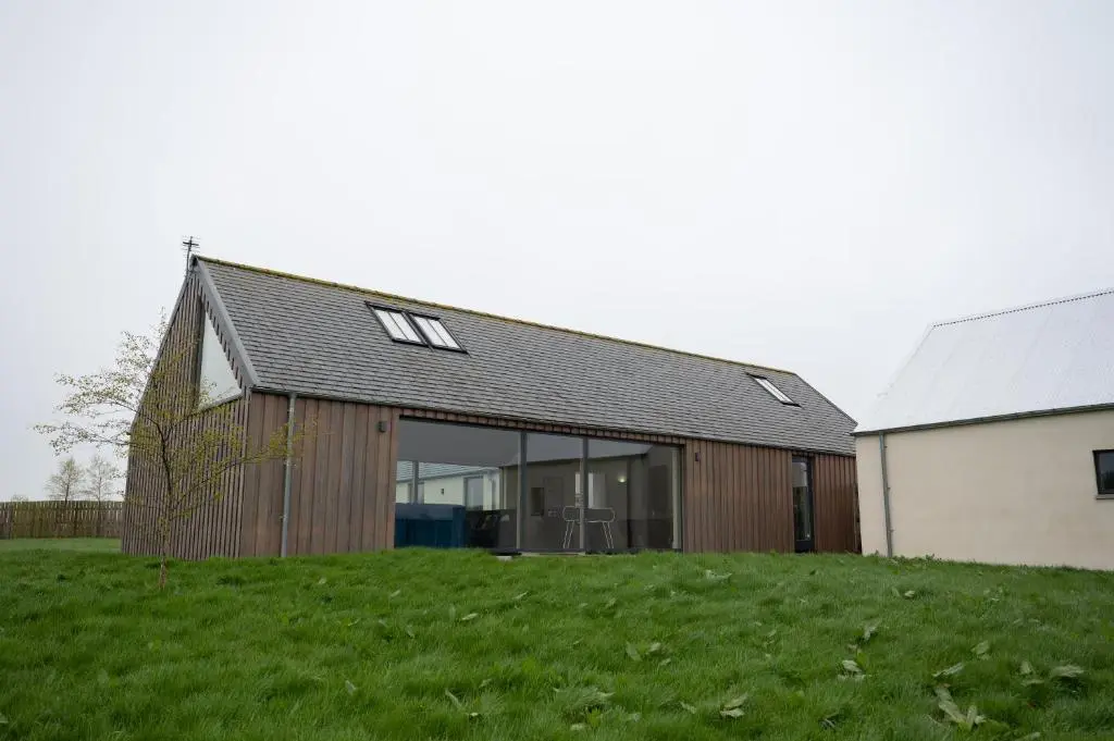 a barn with sliding glass doors on a green field at Stunning Rural Retreat Sleeps\u00a024 in Aberdeen