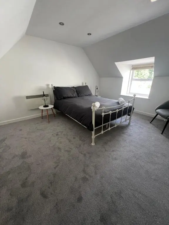 a bedroom with a bed and a chair and a window at MaCaMor in Helmsdale