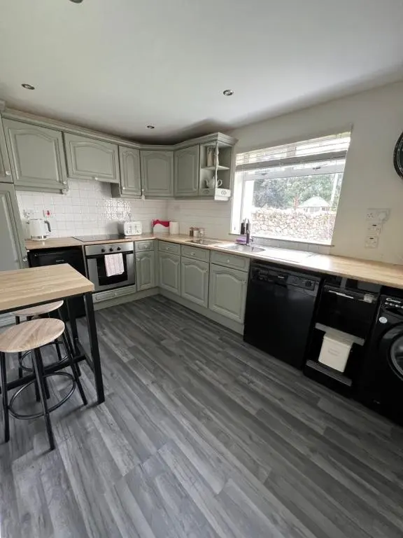a kitchen with green cabinets and a wooden floor at MaCaMor in Helmsdale