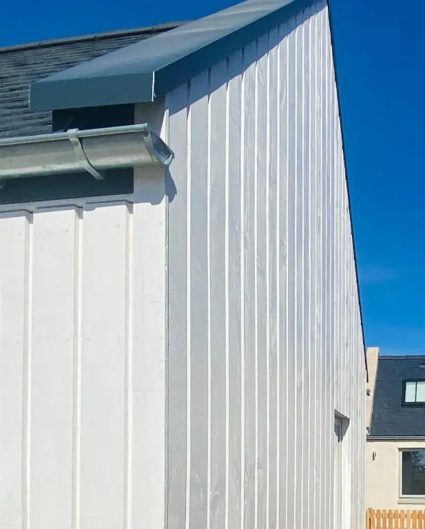 a white building with a blue roof at Nana Cottage , Findhorn Village in Findhorn
