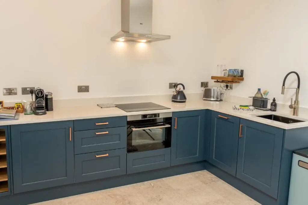 a kitchen with blue cabinets and a sink at Nana Cottage , Findhorn Village in Findhorn