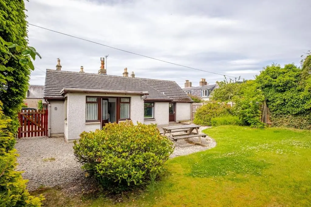 a small cottage with a picnic table in the yard at Applegrove, perfect 2 bed bungalow, Fortrose in Fortrose