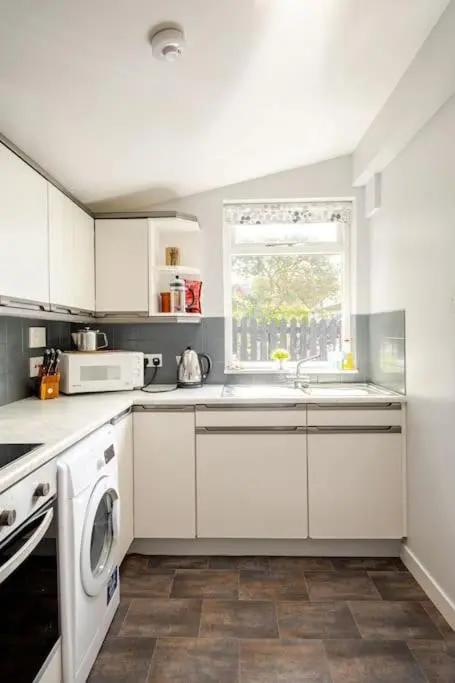a white kitchen with a sink and a dishwasher at Applegrove, perfect 2 bed bungalow, Fortrose in Fortrose