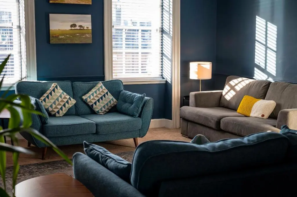 a living room with blue walls and couches and windows at River View City Centre- Free Parking in Inverness