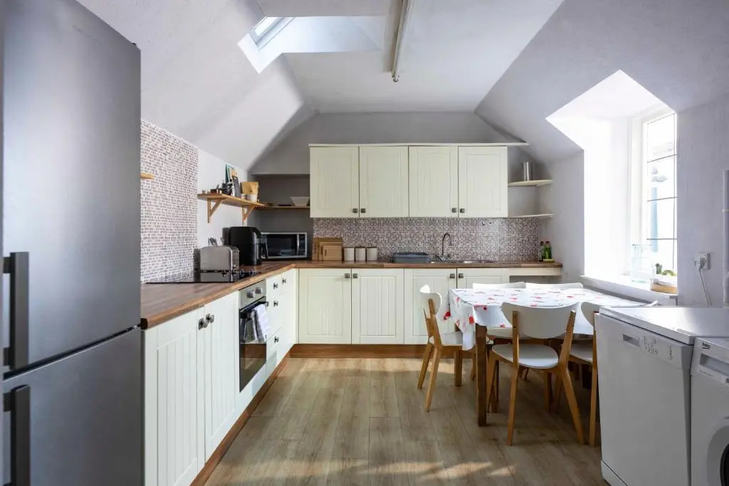 a kitchen with white cabinets and a table with chairs at River View City Centre- Free Parking in Inverness