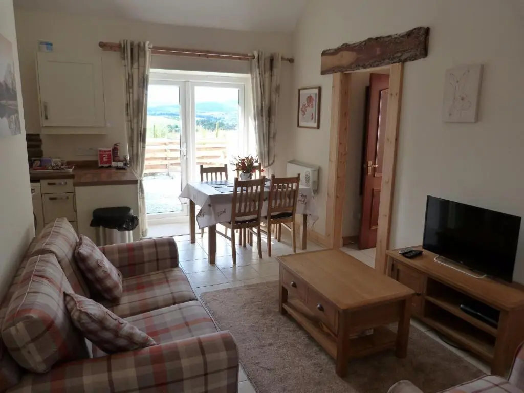 a living room with a couch and a tv and a table at Broomhead Cottages in Dufftown