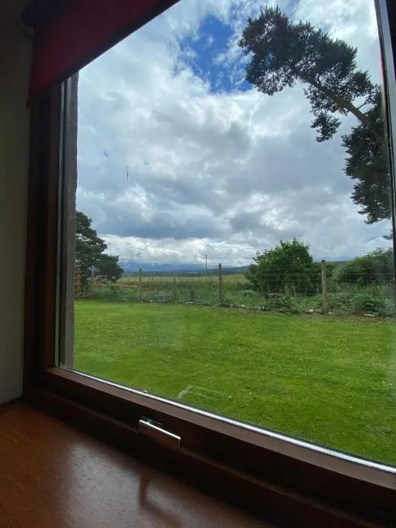 a window with a view of a field of grass at Columba House in Kingussie