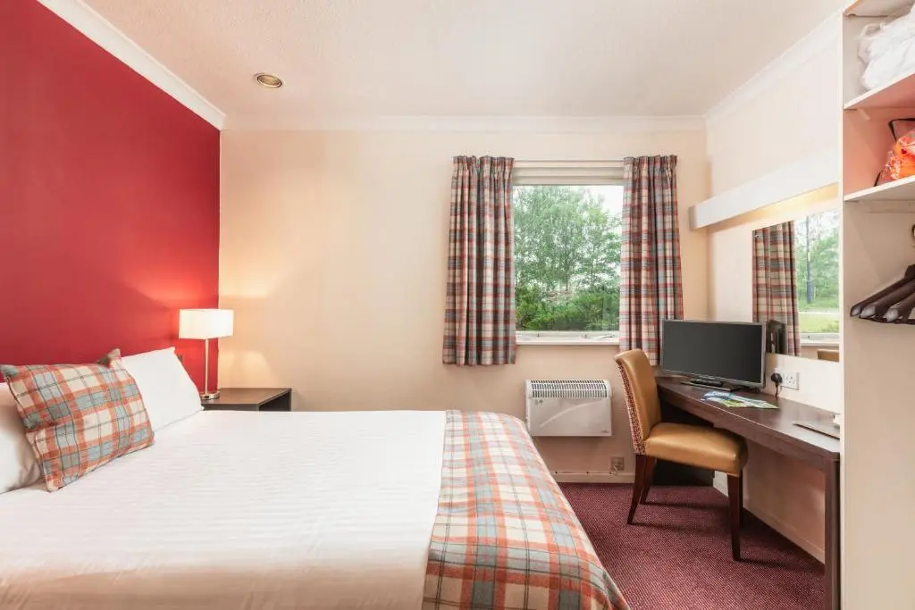 a hotel room with a bed and a desk and a computer at Highlander Hotel \u2018A Bespoke Hotel\u2019 in Newtonmore
