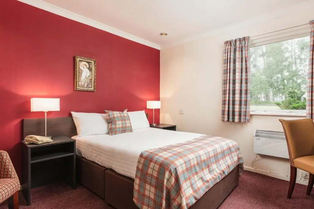 a hotel room with a bed and a red wall at Highlander Hotel \u2018A Bespoke Hotel\u2019 in Newtonmore