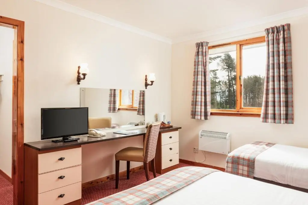 a bedroom with a desk with a computer and a bed at Highlander Hotel \u2018A Bespoke Hotel\u2019 in Newtonmore