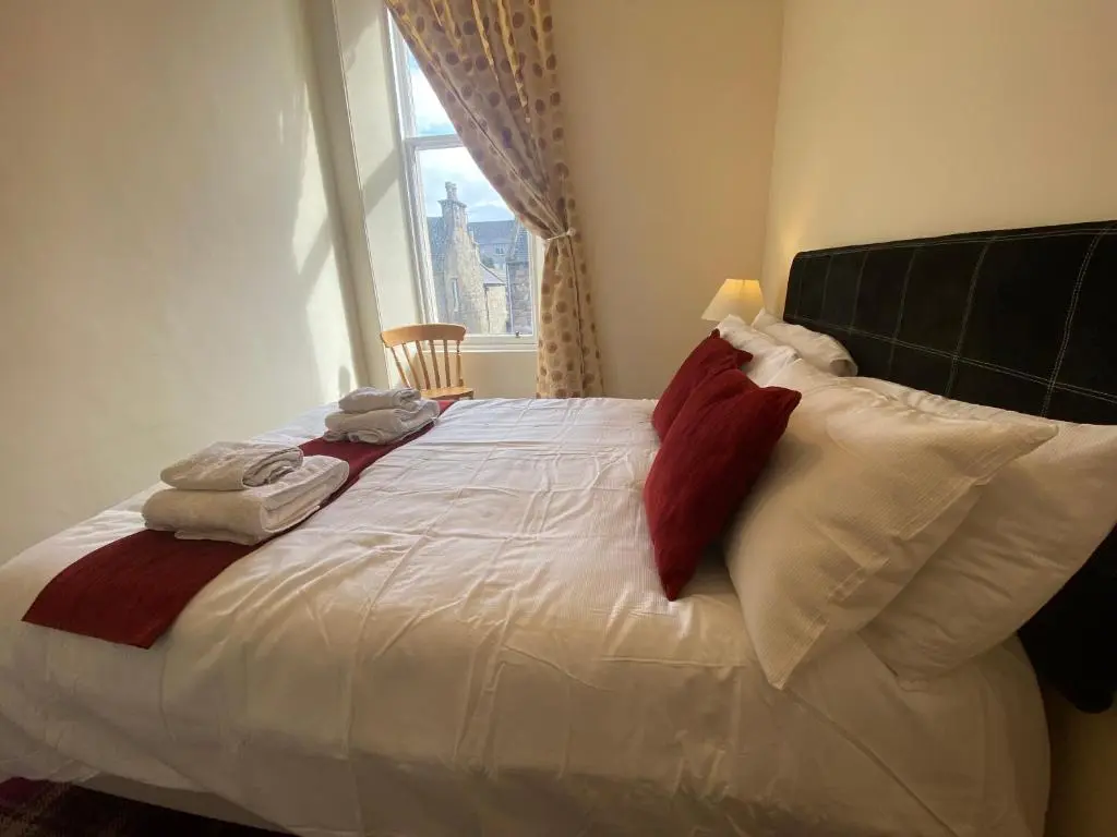 a bedroom with a white bed with red and white pillows at 92 High Street in Aberlour
