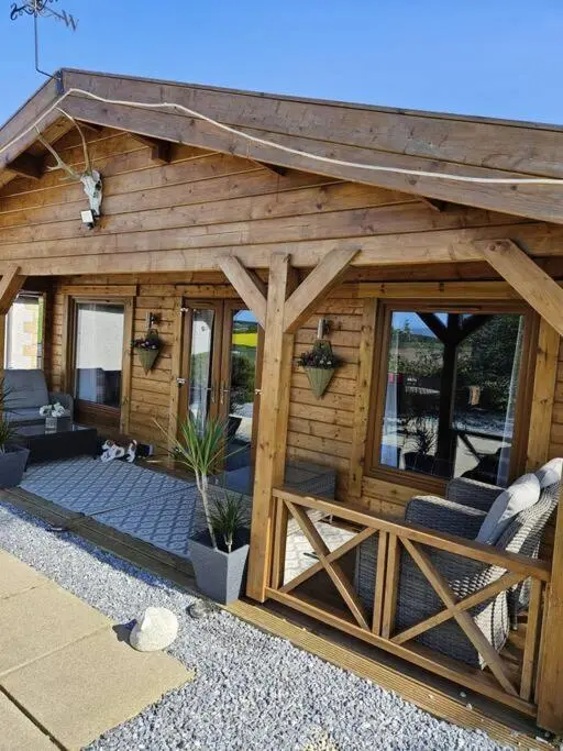 a wooden cabin with a fence and a porch at Hillhaven Lodge in Inverness