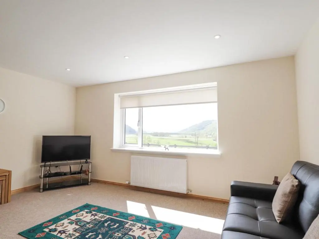 a living room with a couch and a tv and a window at Crask Bungalow in Beauly