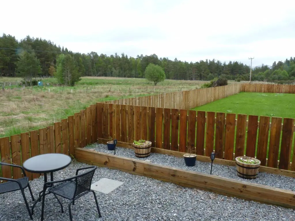 a backyard patio with a fence and a table and chairs at Tanleys - Skye Pod in Grantown on Spey