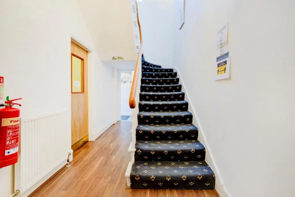 a staircase in a house with a blue and black carpet at OYO Eastbank Hotel, Speyside Scotland in Rothes