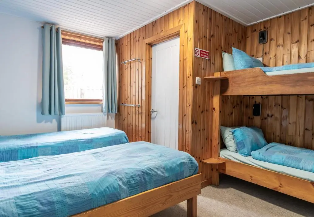 a bedroom with two bunk beds and a window at Insh Hall Rooms at Loch Insh in Kincraig