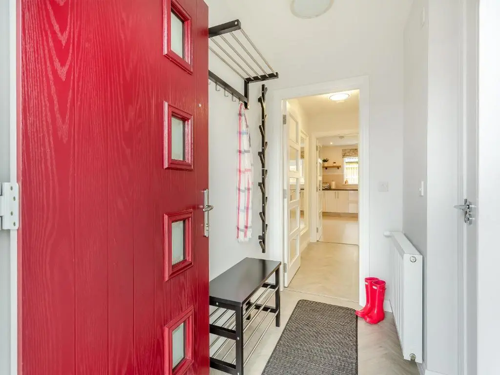 a red door leading to a hallway with a red floor at The Beech House in Aviemore