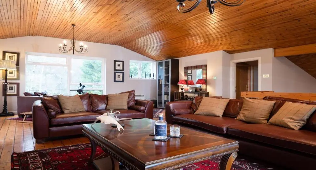 a living room with leather couches and a table at Four Pines Lodge in Skye of Curr