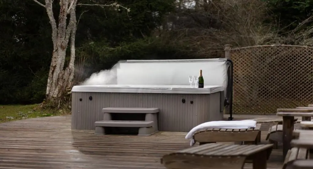 a hot tub with a bottle of wine on a deck at Four Pines Lodge in Skye of Curr