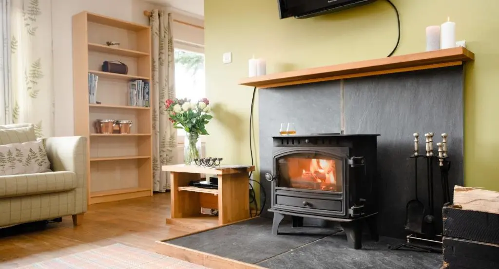 a living room with a fireplace and a couch at Salmon Run Lodge in Carrbridge