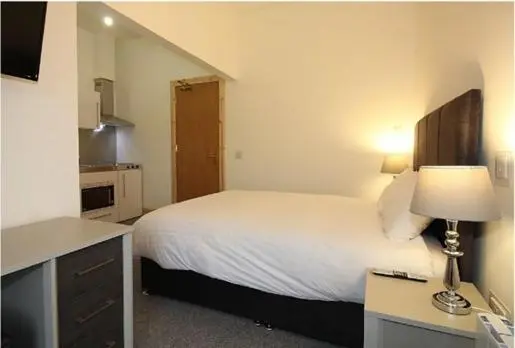 a bedroom with a bed and a desk with a lamp at Duchally House in Nairn