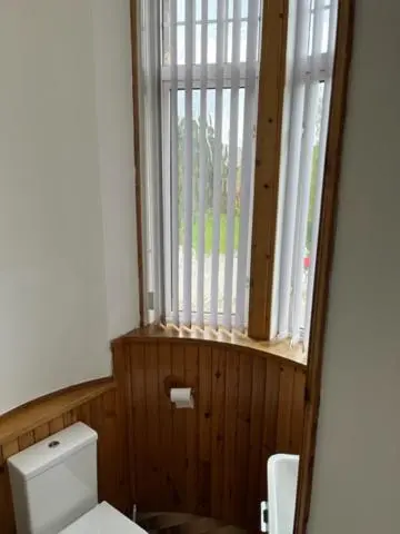 a bathroom with a toilet and a window at Duchally House in Nairn