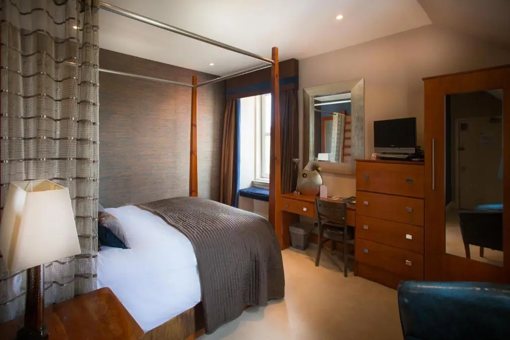 a bedroom with a bed and a desk and a mirror at Heathmount Hotel in Inverness