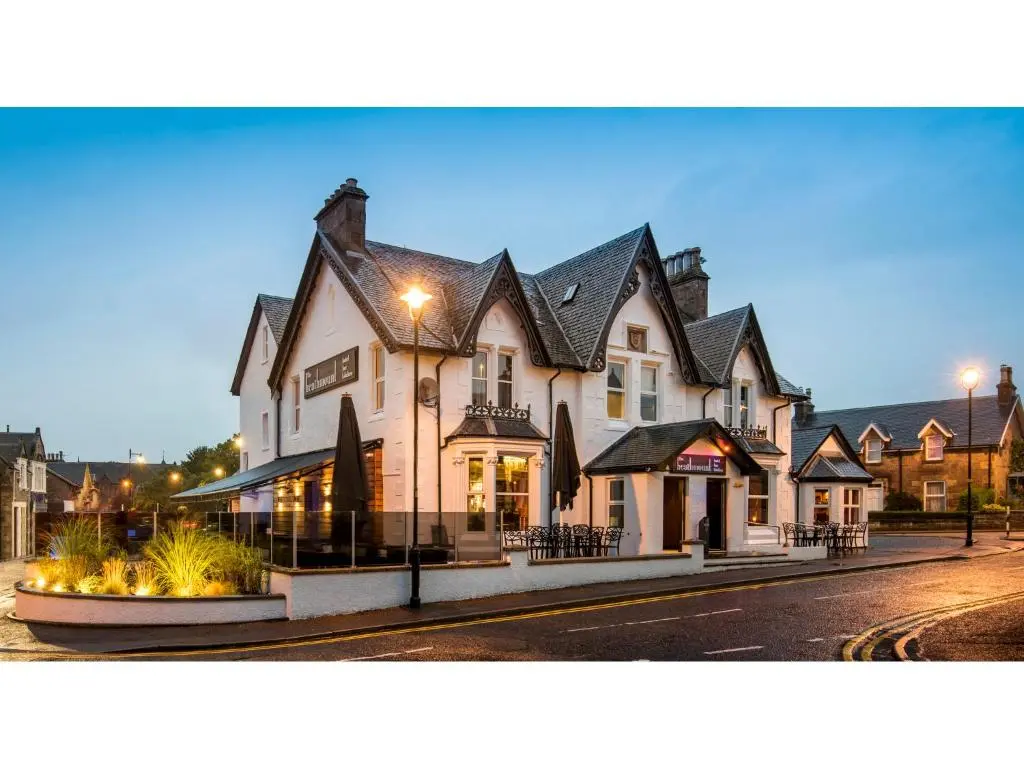 a large white building with black roofs on a street at Heathmount Hotel in Inverness