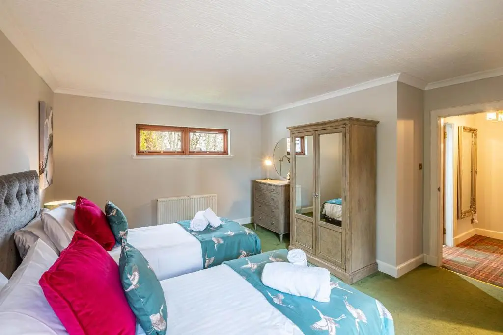 a hotel room with two beds and a mirror at Corrie House with Hot Tub in Belladrum