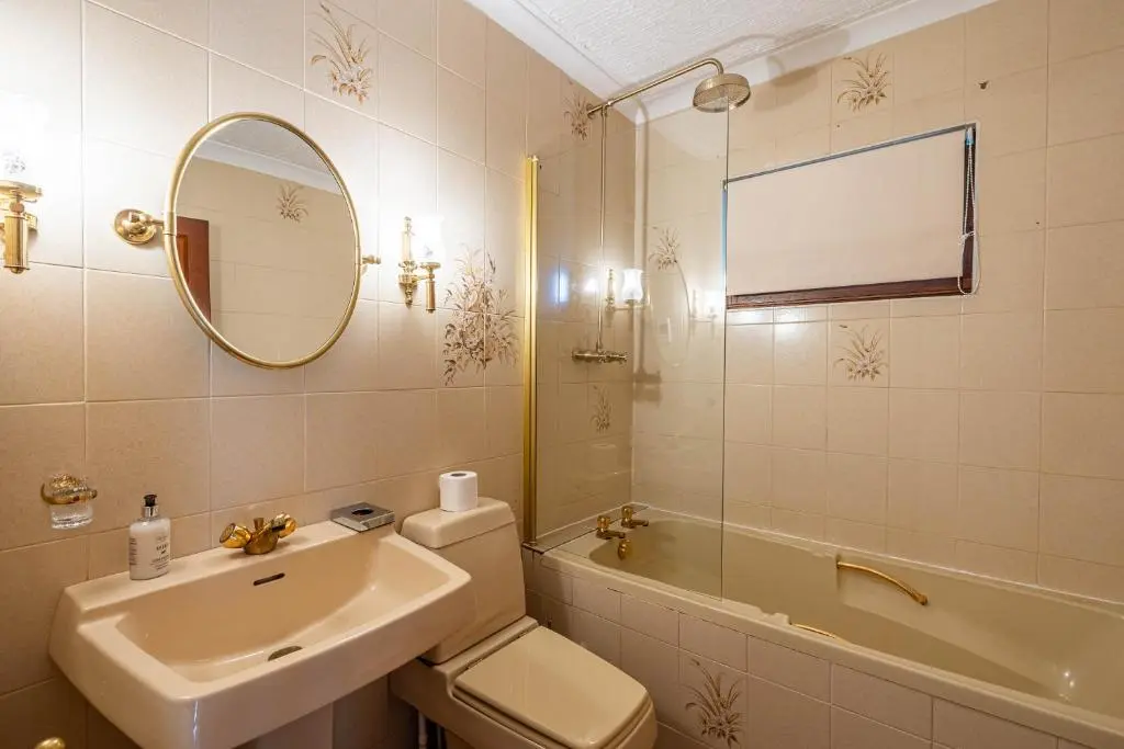 a bathroom with a sink and a toilet and a mirror at Corrie House with Hot Tub in Belladrum