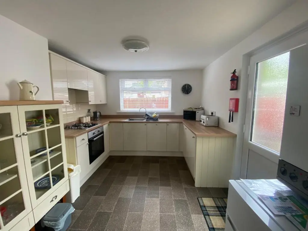 a large kitchen with white cabinets and a window at Stanford House in Inverness