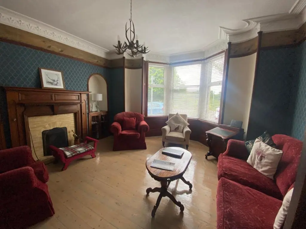 a living room with red furniture and a fireplace at Stanford House in Inverness