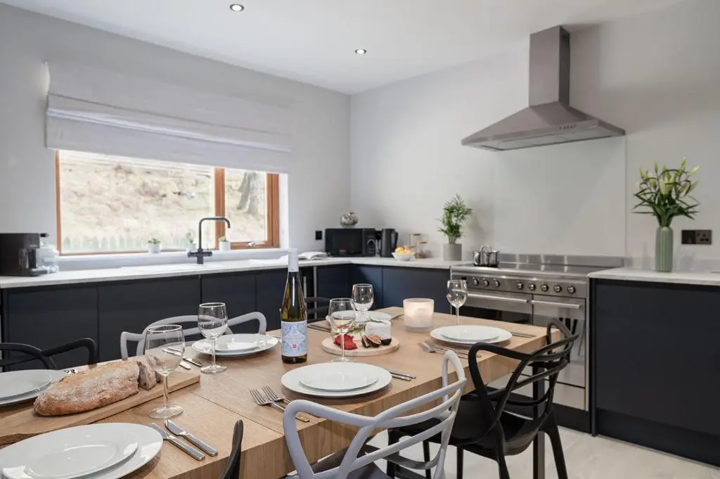 a kitchen with a wooden table with chairs and a dining room at Gardeners Cottage - Seasgair Lodges in Aviemore
