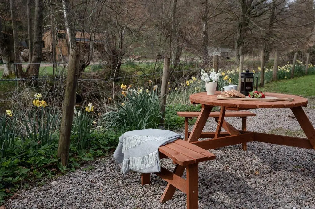 a picnic table and bench in a garden with flowers at Gardeners Cottage - Seasgair Lodges in Aviemore