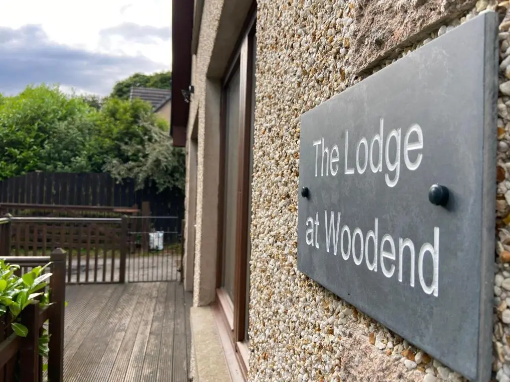 a sign that says the lodge at woodomed on a building at The Lodge at Woodend in Kemnay