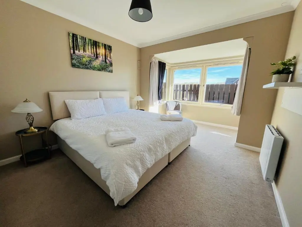a bedroom with a large white bed with a window at The Lodge at Woodend in Kemnay