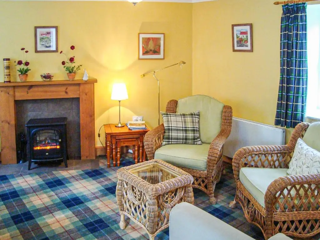 a living room with chairs and a fire place at The Bothy At Willowbank in Grantown on Spey